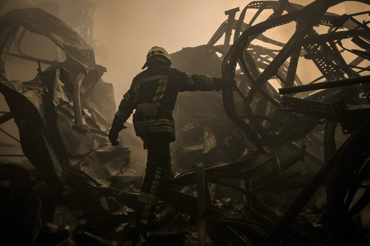 A Ukrainian firefighter walks inside a large food products storage facility which was destroyed ...