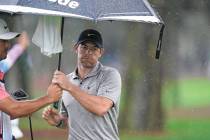 Rory McIlroy, of Northern Ireland, tries to stay dry on ninth green during the first round of p ...