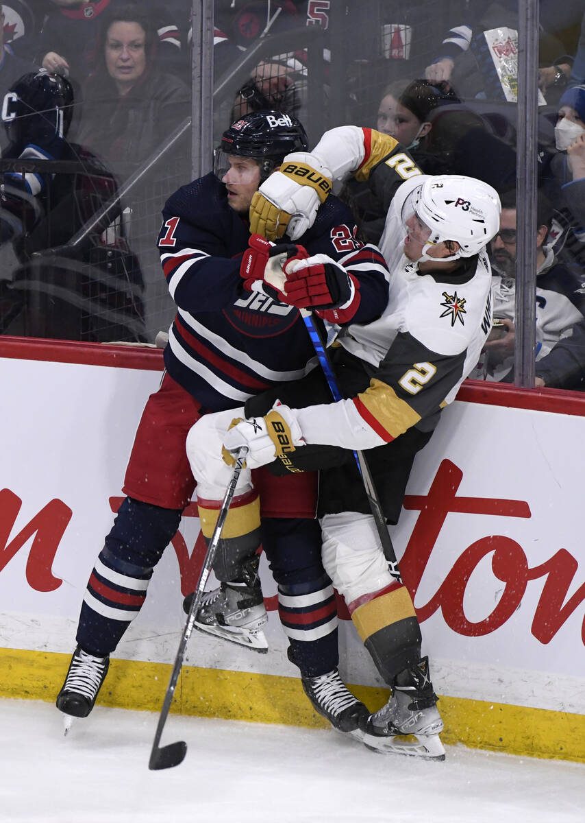 Winnipeg Jets' Dominic Toninato (21) checks Vegas Golden Knights' Zach Whitecloud (2) during th ...