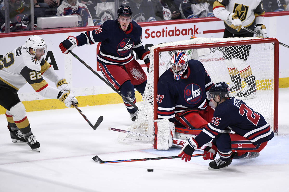 Vegas Golden Knights' Michael Amadio (22) passes the puck past Winnipeg Jets goaltender Connor ...
