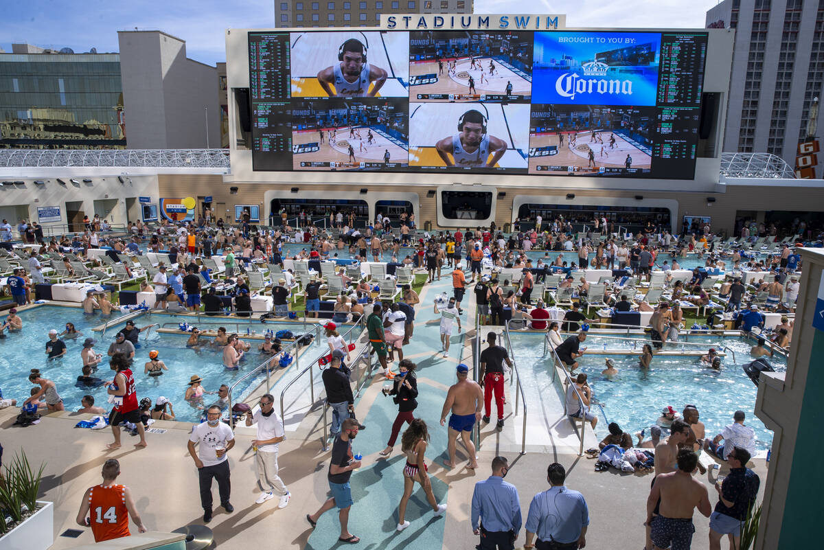 The pools and decks are crowded at Stadium Swim as March Madness is projected above at the Circ ...