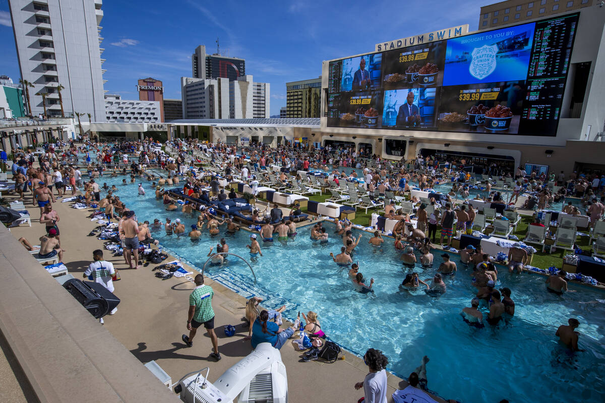 The pools and decks are crowded at Stadium Swim as March Madness is projected above at the Circ ...