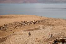 A family walks over cracked mud near Lake Oroville's shore in Oroville, Calif., on Aug. 22, 202 ...