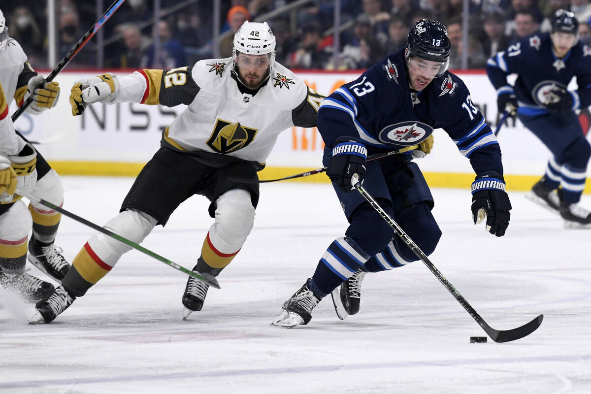 Winnipeg Jets' Zach Sandord (13) is held by Vegas Golden Knights' Daniil Miromanov (42) during ...