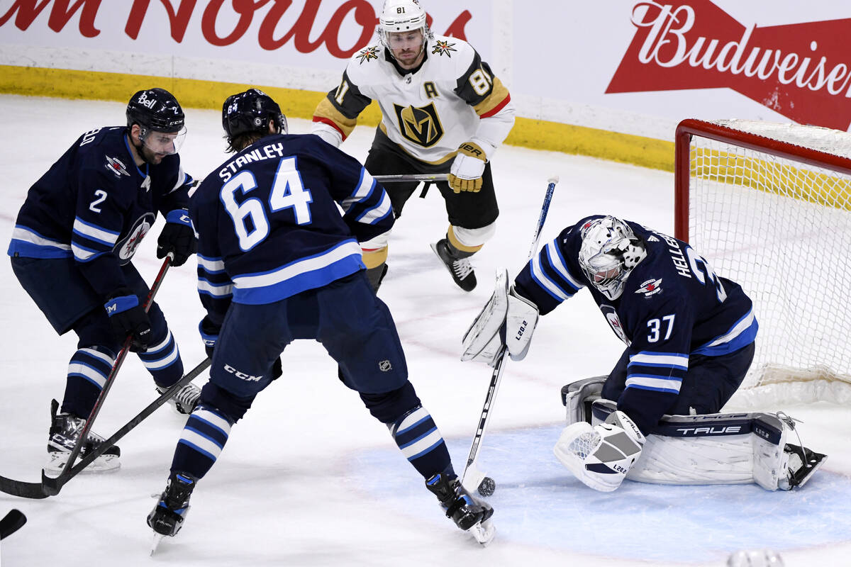 Winnipeg Jets goaltender Connor Hellebuyck (37) covers up the loose puck as Vegas Golden Knight ...