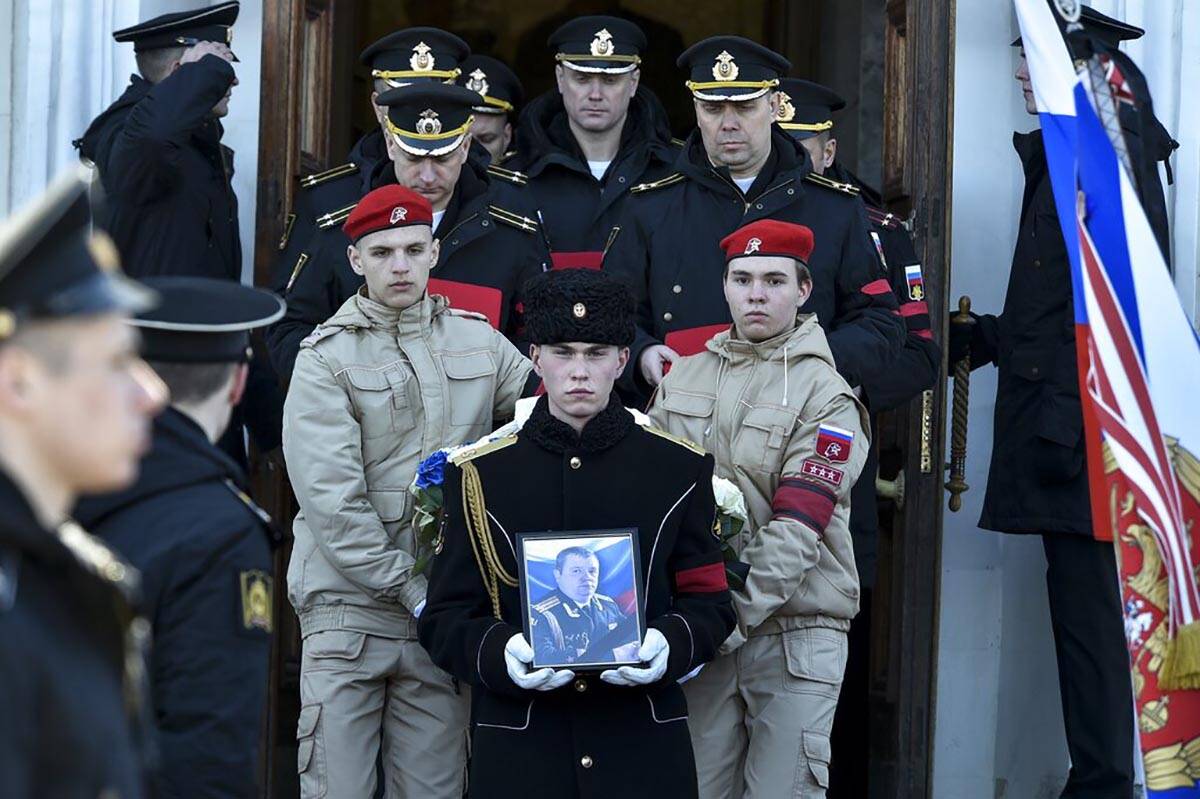 A serviceman carries the photo of Capt. Andrei Paliy, a deputy commander of Russia's Black Sea ...