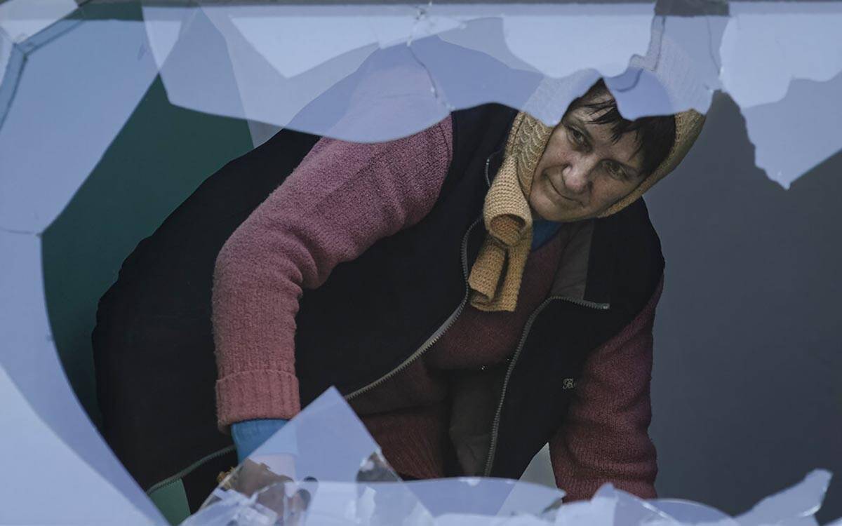 A woman cleans the staircase of broken glass at an apartment building damaged by bombing in Kyi ...