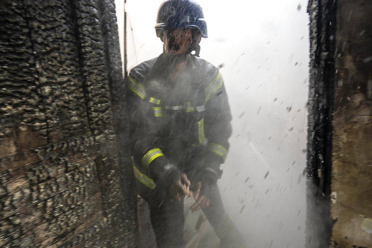 A Ukrainian firefighter shouts to a colleague while trying to extinguish a fire inside a house ...