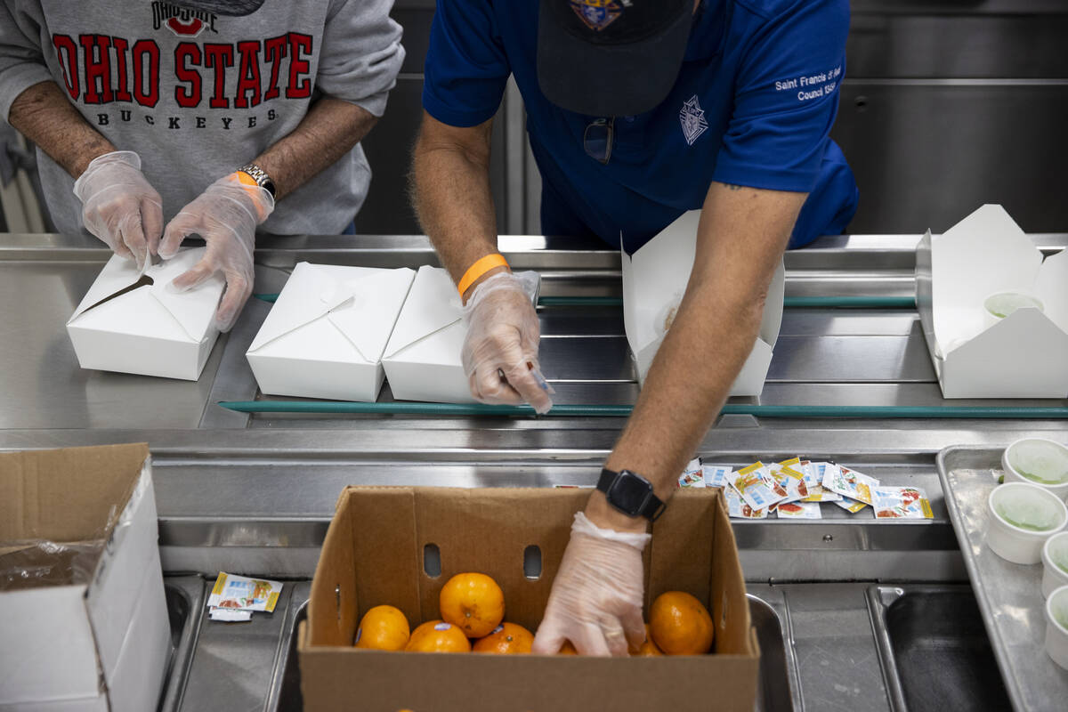Volunteers package after school lunches at the Three Square North Campus in Las Vegas, Thursday ...