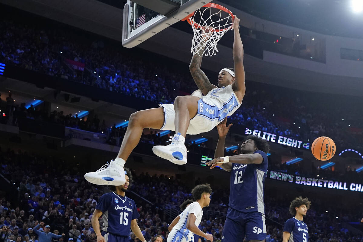 North Carolina's Armando Bacot, left, hangs on the rim after a dunk past St. Peter's Clarence R ...