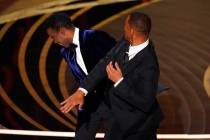Will Smith, right, hits presenter Chris Rock on stage while presenting the award for best docum ...