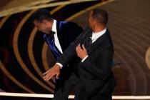 Will Smith, right, hits presenter Chris Rock on stage while presenting the award for best docum ...