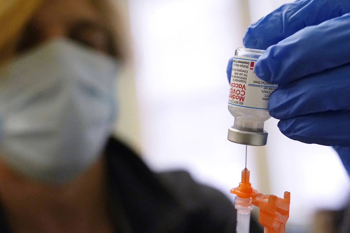 Pharmacist Kenni Clark prepares a booster dose of the Moderna COVID-19 vaccine during a vaccina ...