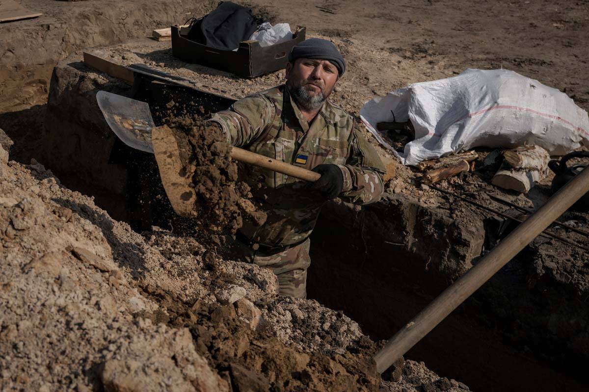 A Ukrainian serviceman digs a trench at a position north of the capital Kyiv, Ukraine, Tuesday, ...