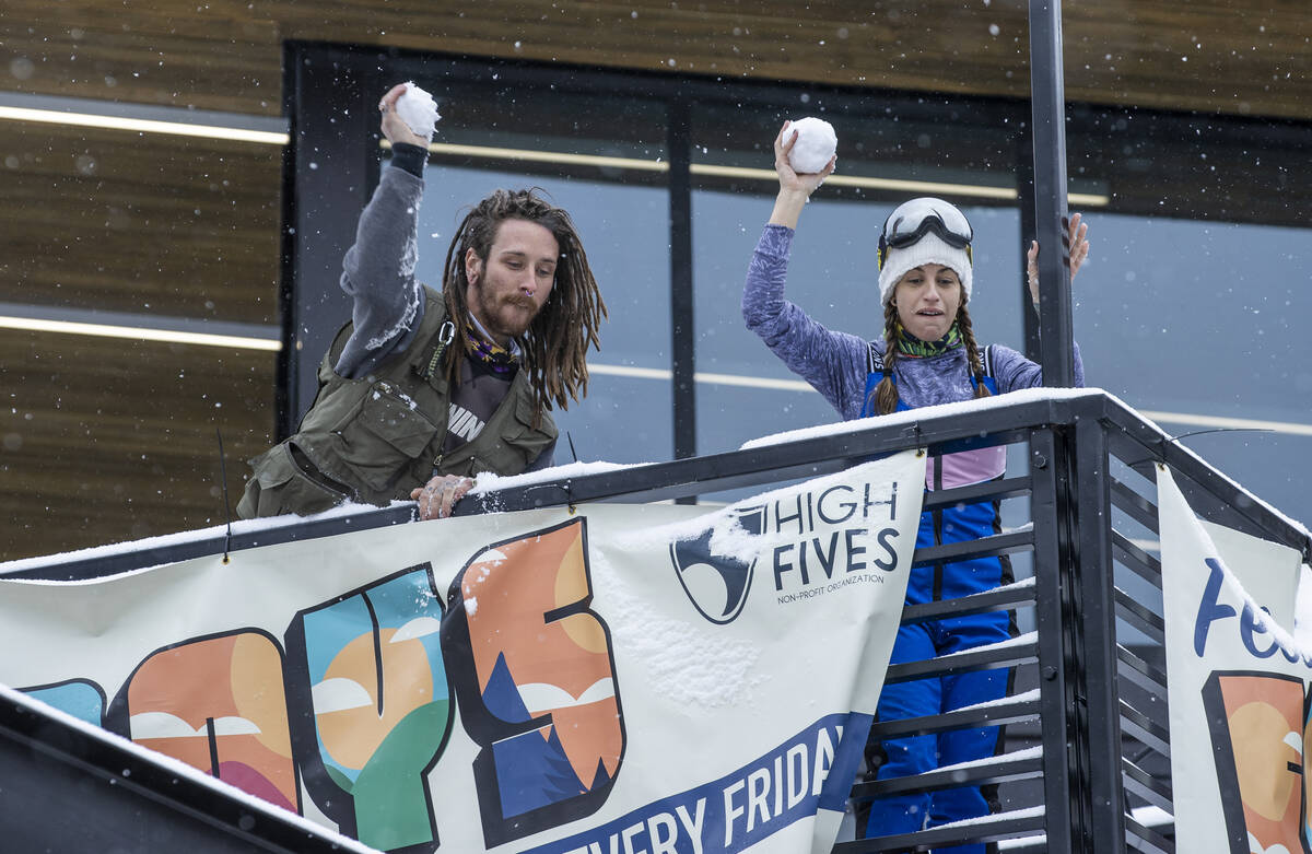Justin Randall and Caroline Bye, both of Las Vegas, toss snowballs down towards a friend while ...