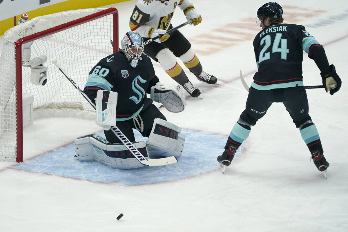 Seattle Kraken goaltender Chris Driedger (60) and defenseman Jamie Oleksiak (24) eye the puck d ...