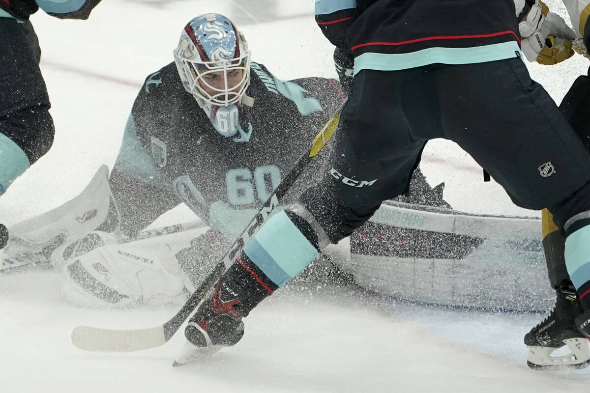 Ice flies as Seattle Kraken goaltender Chris Driedger (60) stops a shot by the Vegas Golden Kni ...