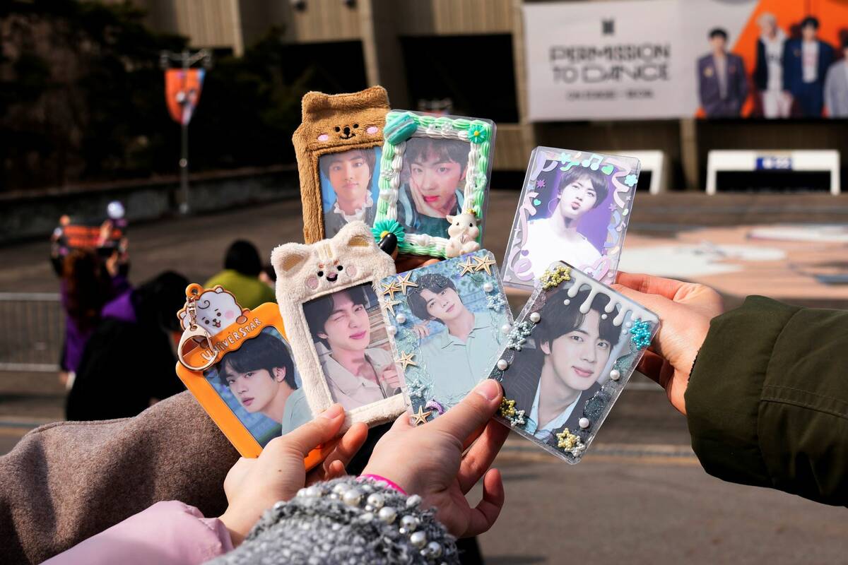 Fans of South Korean K-pop band BTS show their photos of BTS members as they arrived for the co ...