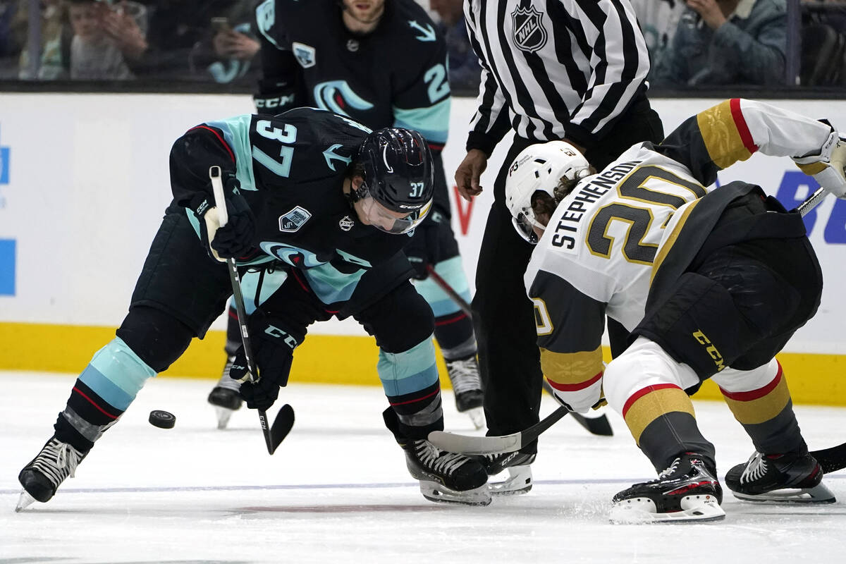 Vegas Golden Knights' Chandler Stephenson sends the puck past Seattle Kraken's Yanni Gourde on ...