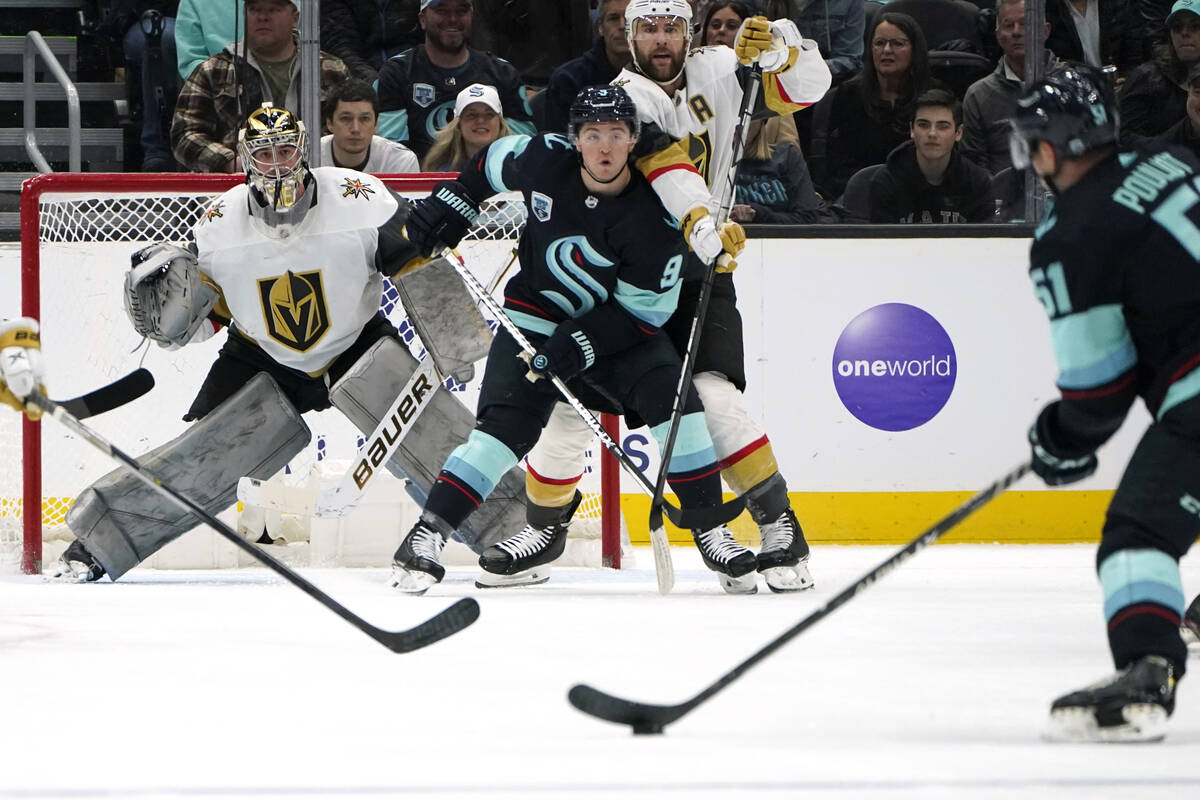 Vegas Golden Knights goaltender Logan Thompson, left, eyes the puck as Seattle Kraken's Derrick ...