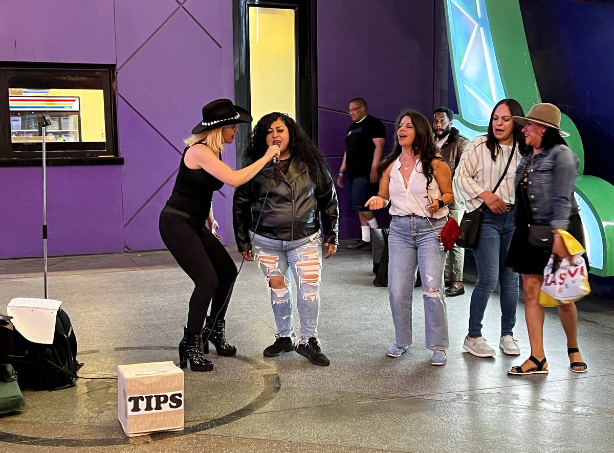 A street performer has a visitor join in singing Tejano music as friends dance along about a de ...