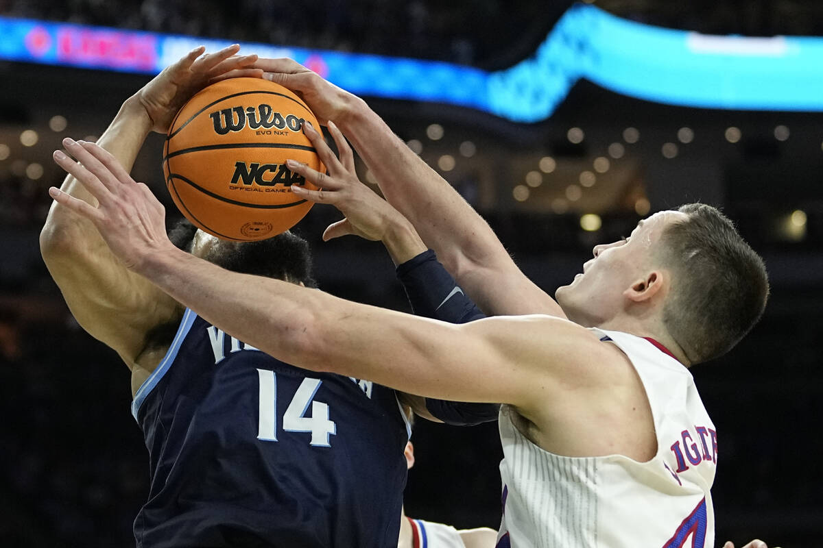 Kansas forward Mitch Lightfoot, right, blocks a shot by Villanova guard Caleb Daniels during th ...