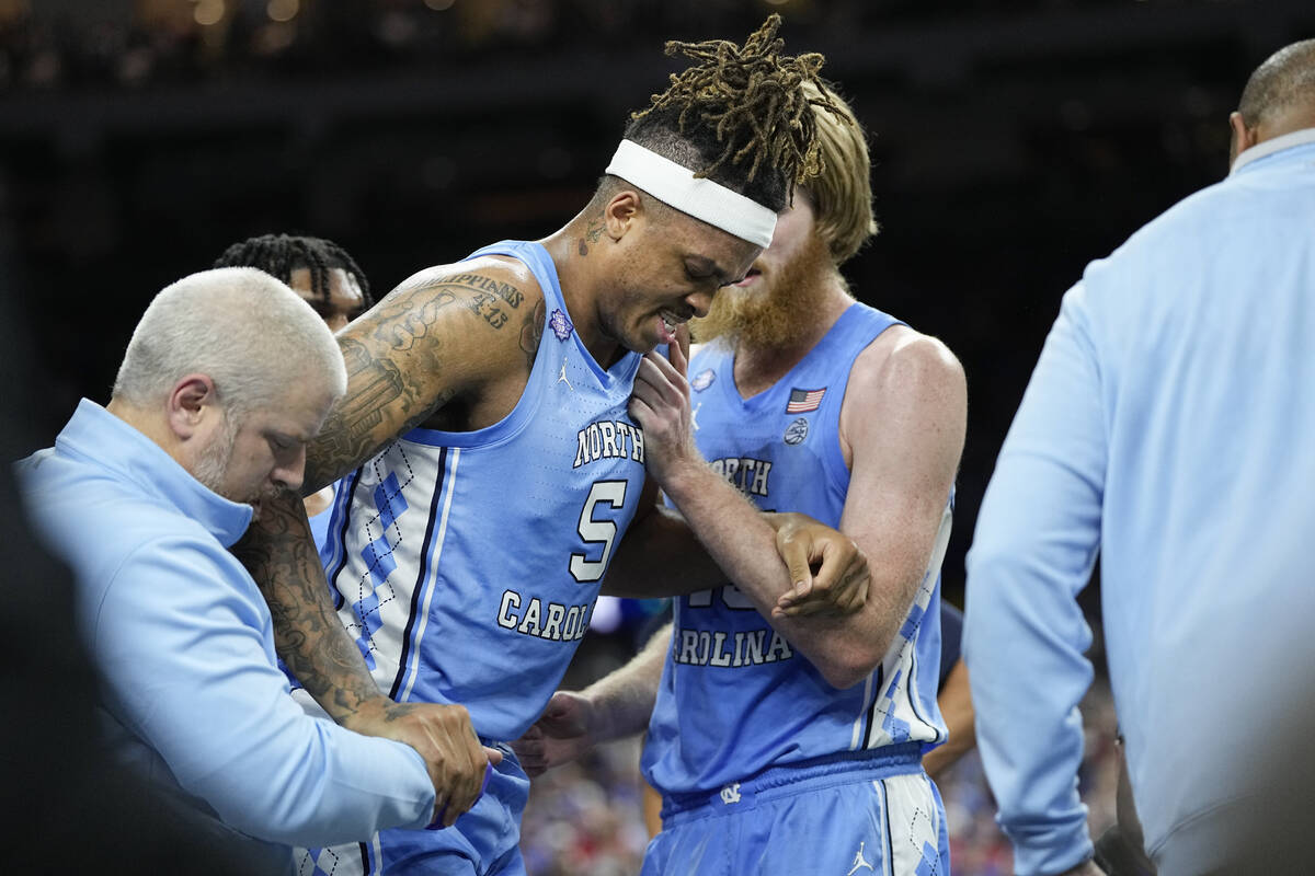 North Carolina forward Armando Bacot is helped off the court during the second half of a colleg ...