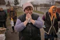 A woman cries while waiting along with others for distribution of food products in the village ...