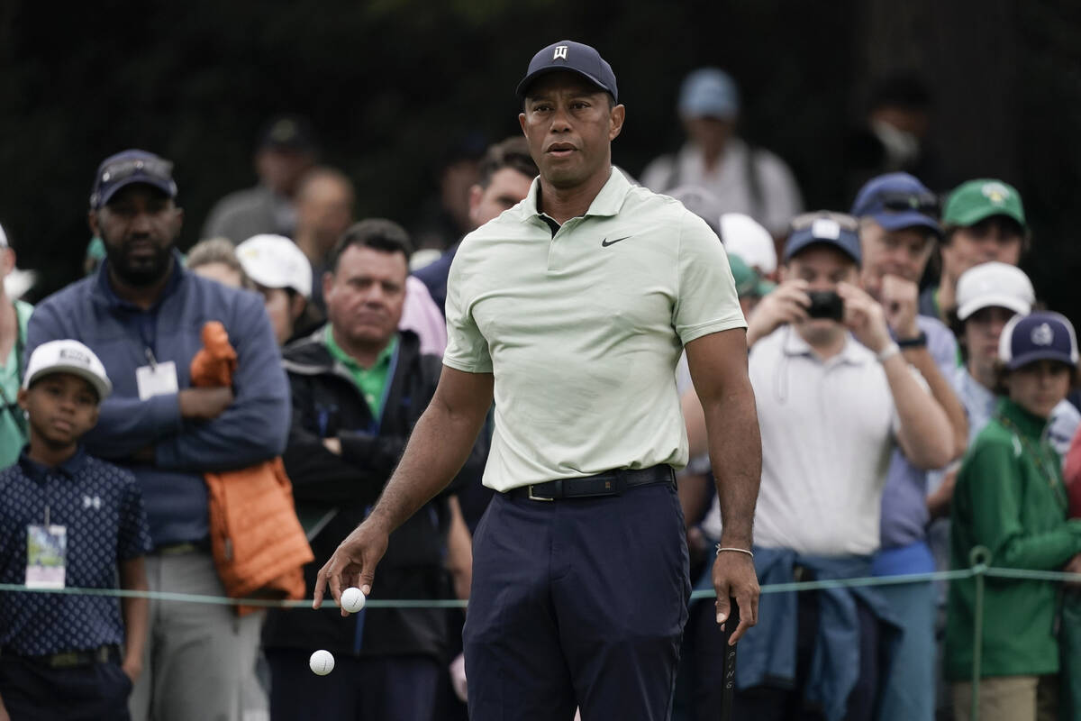 Tiger Woods drops golf balls on the driving range during a practice round for the Masters golf ...