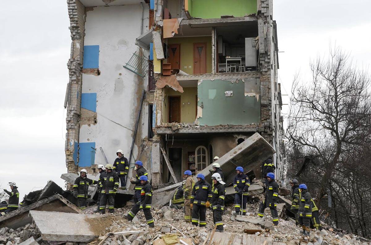 Emergency workers search through the rubble of an apartment building following a Russian attack ...