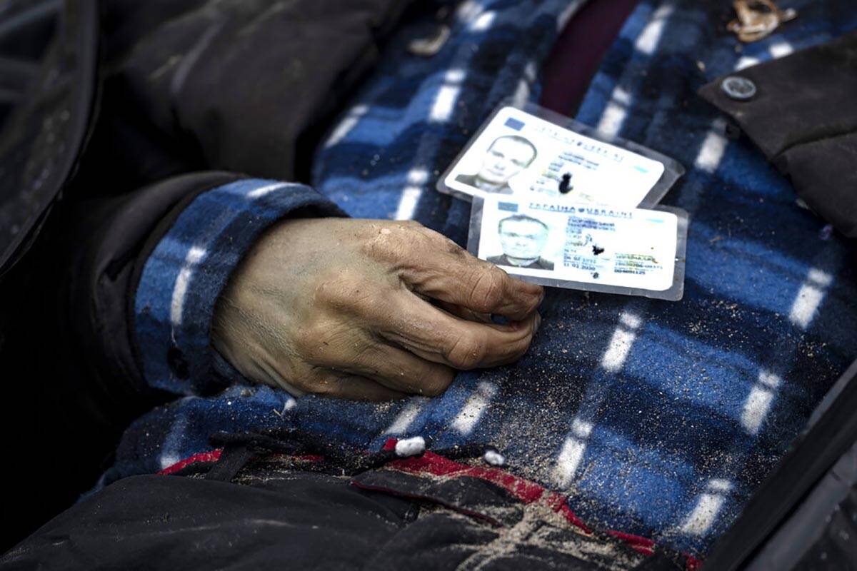Identification cards on a man as policemen work on the indentification process following the ki ...