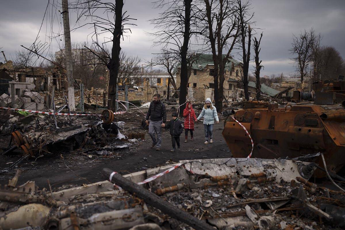 A family walks amid destroyed Russian tanks in Bucha, on the outskirts of Kyiv, Ukraine, Wednes ...