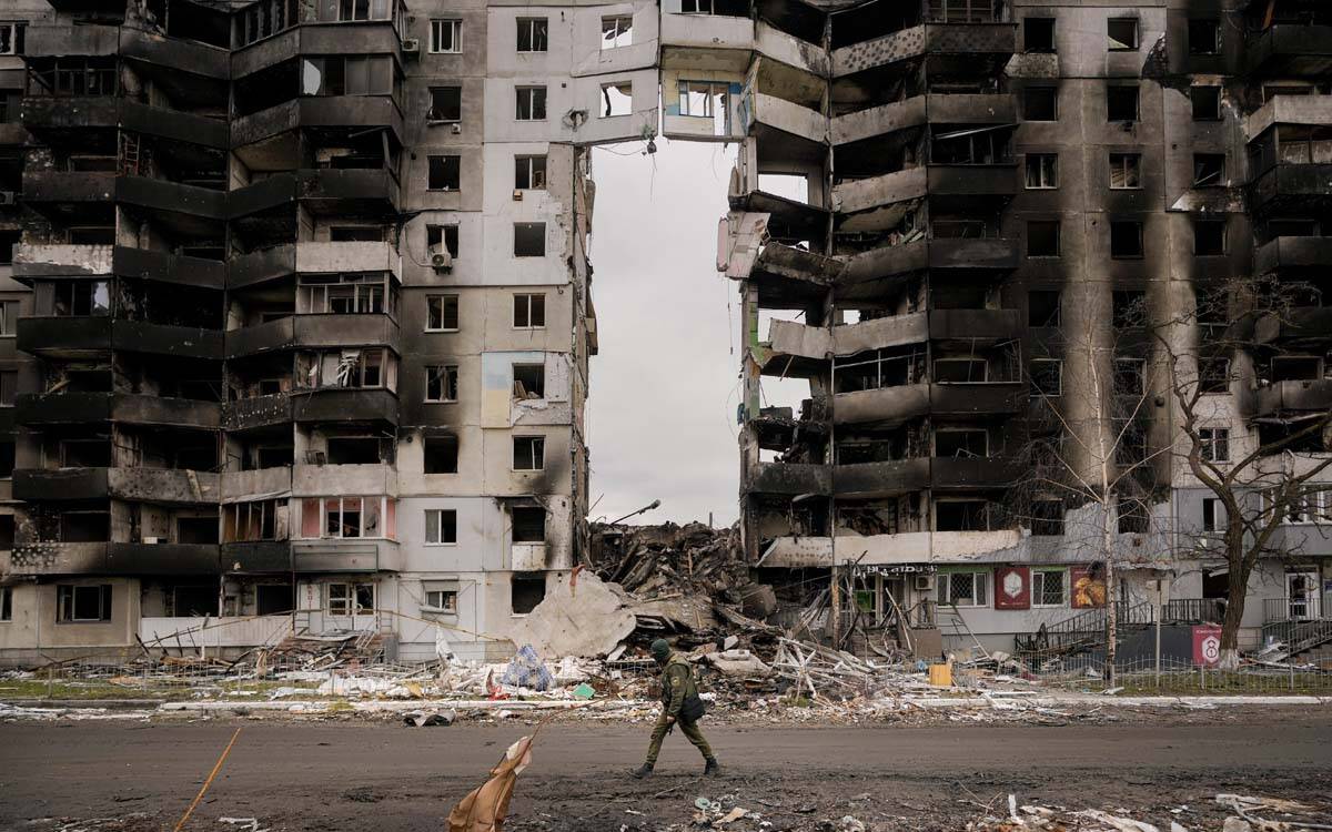 A Ukrainian serviceman walks by a destroyed apartment building in Borodyanka, Ukraine, Wednesda ...