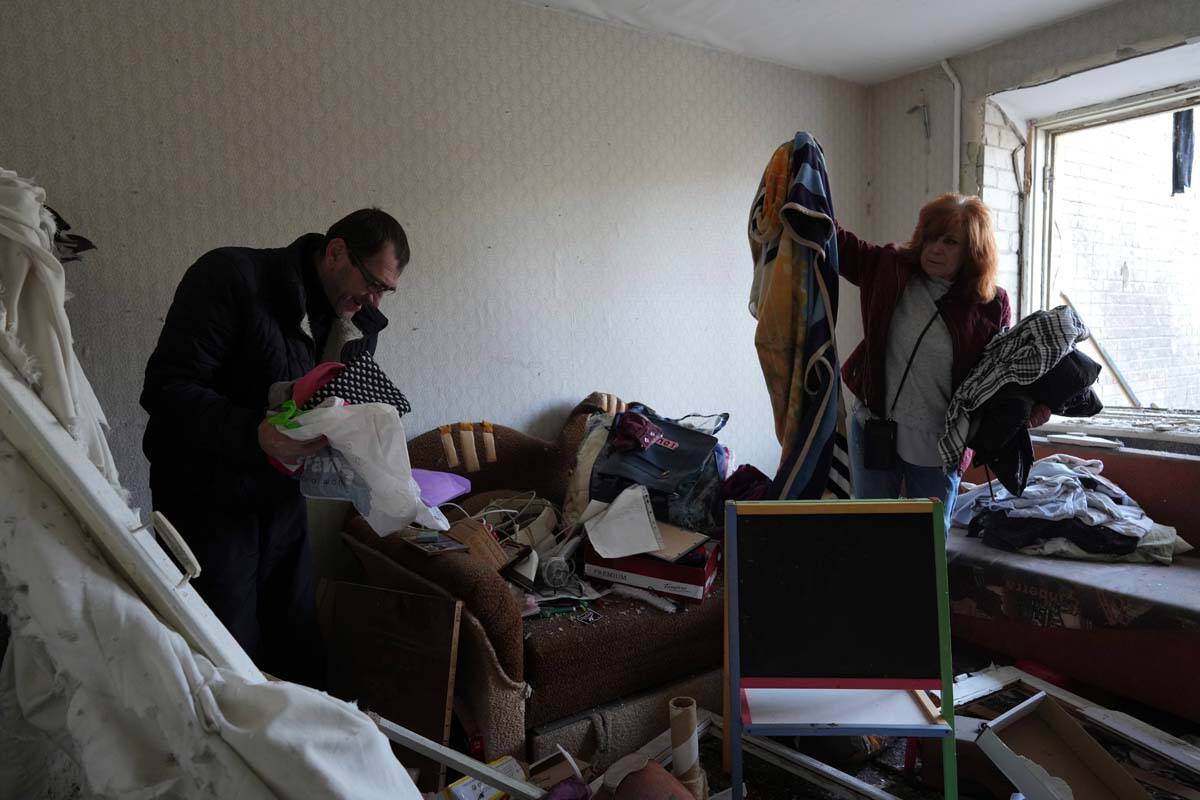 Serhiy, left, and Liumila collect unbroken belongings at their children's apartments damaged by ...