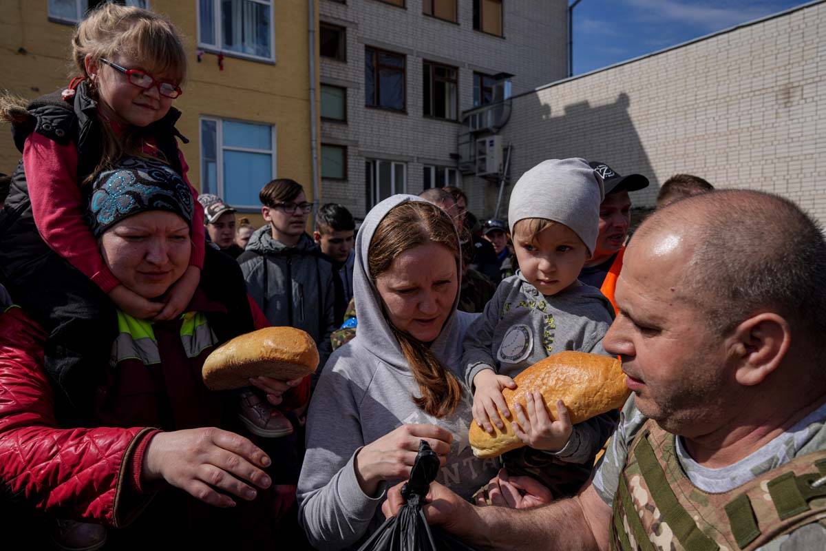 A volunteer, right, distributes humanitarian aid in a yard of a school in Chernihiv, Ukraine, T ...