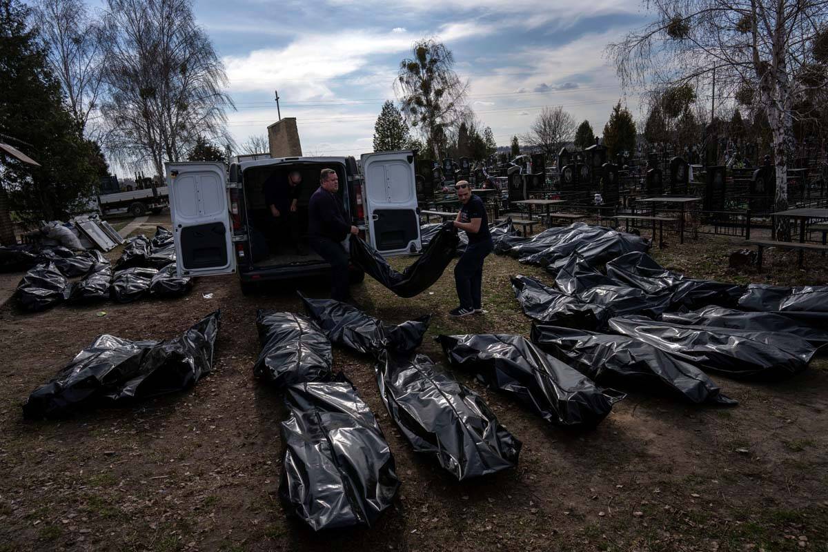 Cemetery workers unload bodies of killed civilians from a van in the cemetery in Bucha, outskir ...