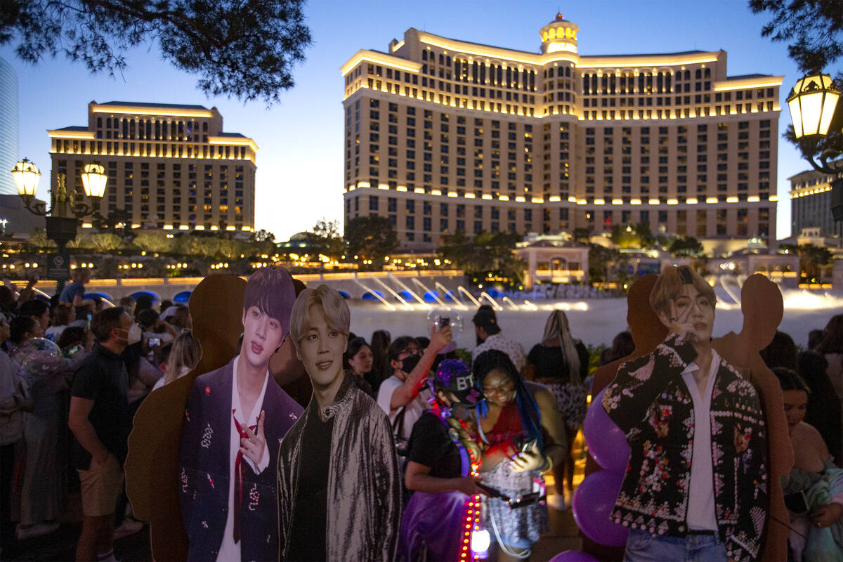 Orang yang lewat memotret guntingan BTS saat mereka menunggu Air Mancur Bellagio ditampilkan di…