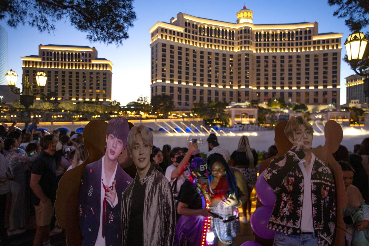 Passersby photograph BTS cutouts while waiting for the Bellagio Fountain to unveil its show to ...