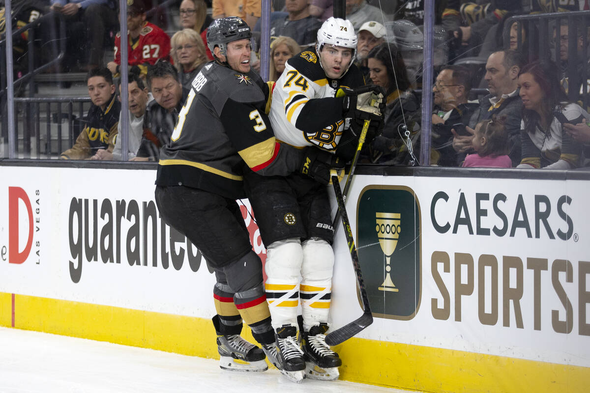 Golden Knights defenseman Brayden McNabb (3) slams Bruins left wing Jake DeBrusk (74) into the ...