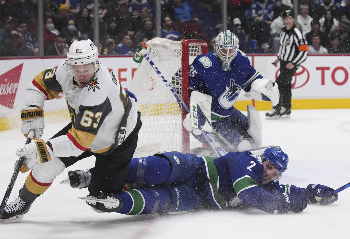 Vegas Golden Knights' Evgenii Dadonov (63) and Vancouver Canucks' Luke Schenn (2) collide in fr ...