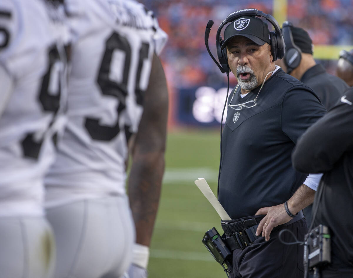 Raiders interim head coach Rich Bisaccia talks to teammates on the sidelines versus the Denver ...