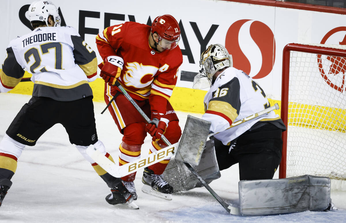 Vegas Golden Knights goalie Logan Thompson, right, tangles with Calgary Flames' Mikael Backlund ...