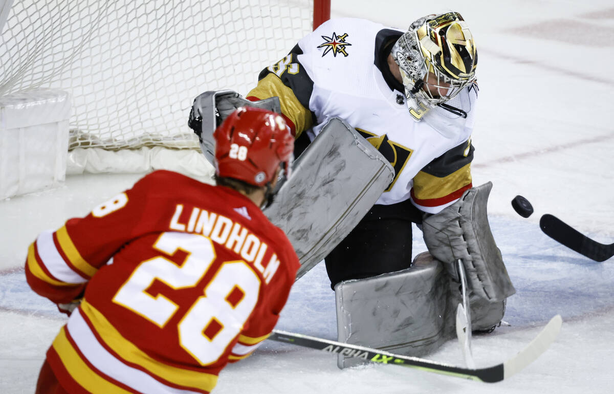 Vegas Golden Knights goalie Logan Thompson, right, blocks a shot from Calgary Flames' Elias Lin ...