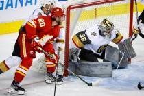 Vegas Golden Knights goalie Logan Thompson, right, blocks the net as Calgary Flames' Blake Cole ...