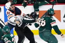 An official, center, gets caught between Edmonton Oilers' Evander Kane (91) and Minnesota Wild' ...