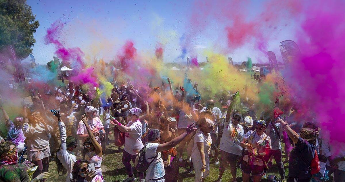 Participants throw colors together as the music continues during the Holi Festival of Colors at ...