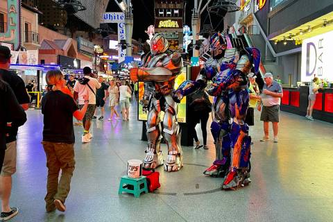 Street performers as Transformers greet a visitor as they pose for photos within a designated c ...