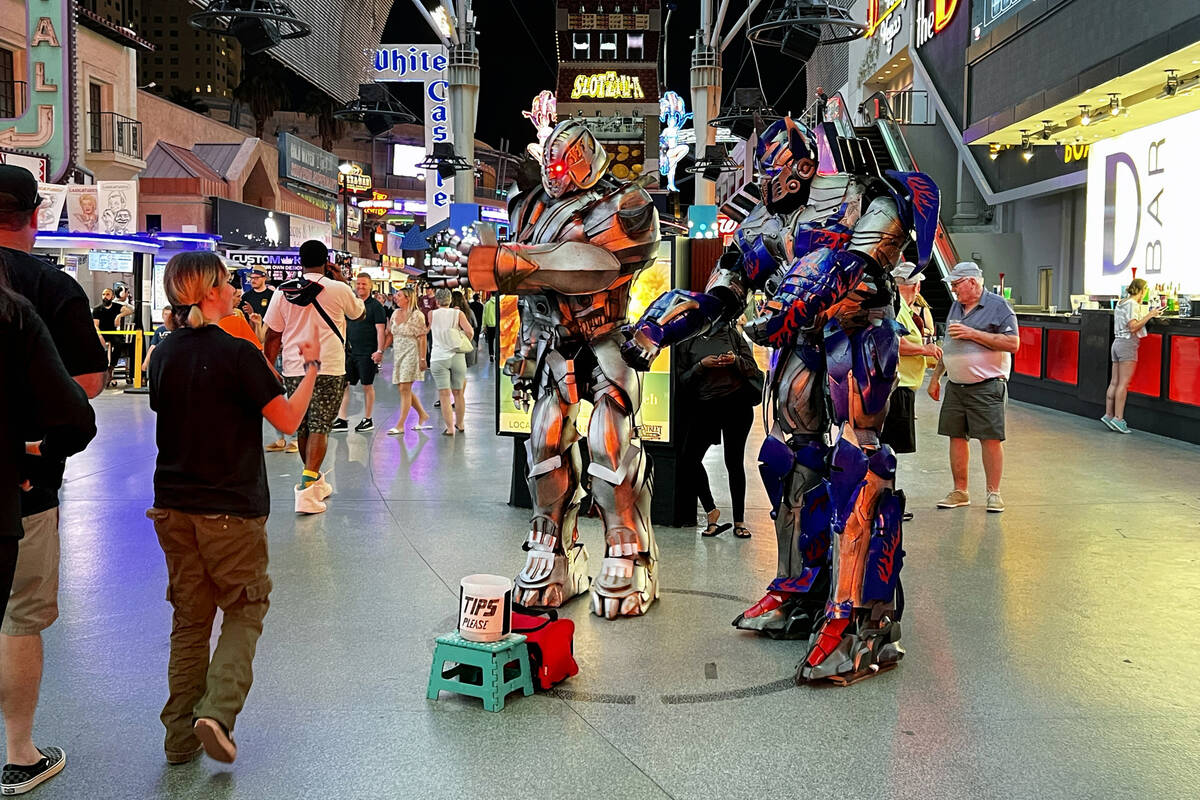 Street performers as Transformers greet a visitor as they pose for photos within a designated c ...