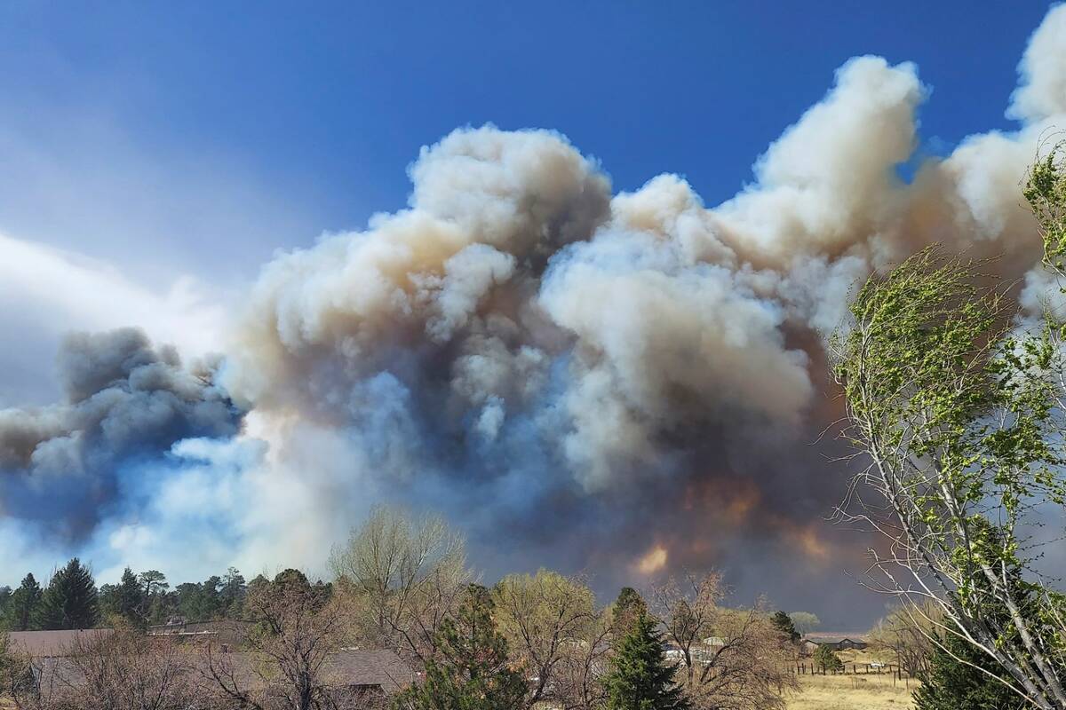 Smoke from a wind-whipped wildfire rises above neighborhoods on the outskirts of Flagstaff, Ari ...