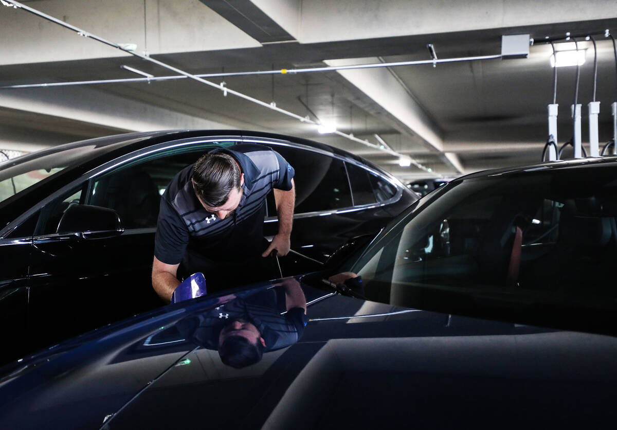 Andrew Pluta, valet manager, plugs in an electric vehicle to charge at Harry Reid International ...